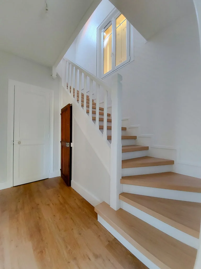 Escalier quart tournant après rénovation : lambris retiré, blanc et bois clair