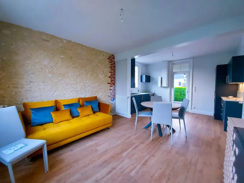 Salon après rénovation : lambris et poutres déposés, parquet clair posé