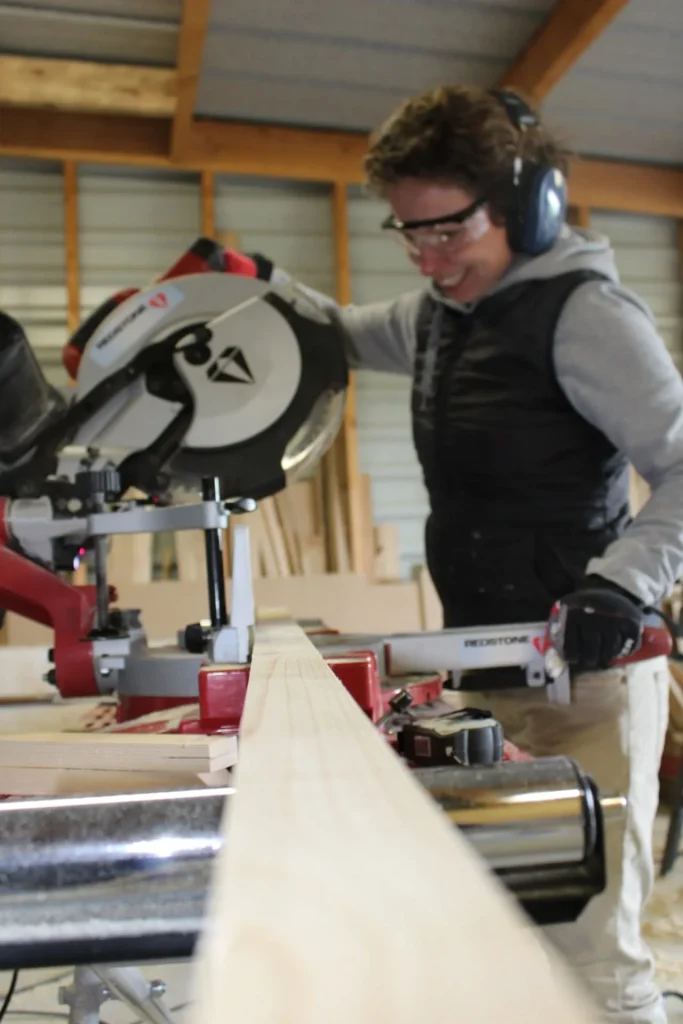 Sarah découpe une pièce de bois à la scie radiale