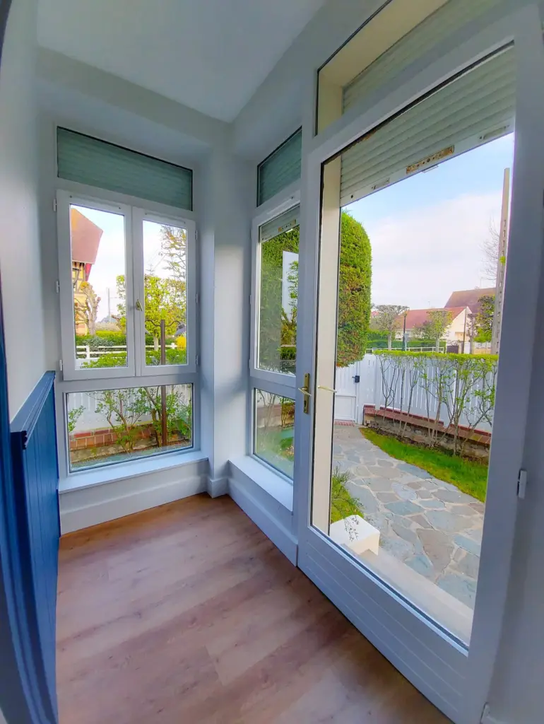 Véranda après rénovation : murs blancs et parquet continu : une pièce à vivre de plus